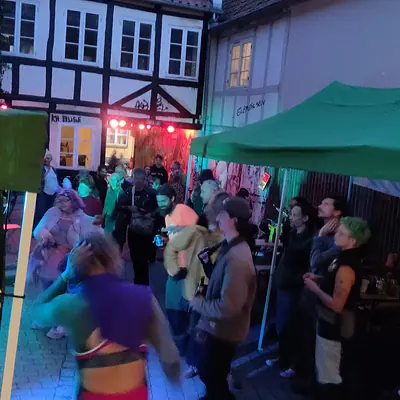 Folk danser til en gadefest om aftenen mellem bindingsværkshuse.