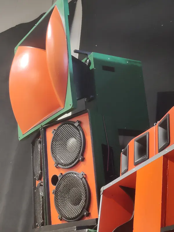 Nærbillede af en orange hornenhed oven på et kabinet med to højttalerenheder, malet orange og grønt.